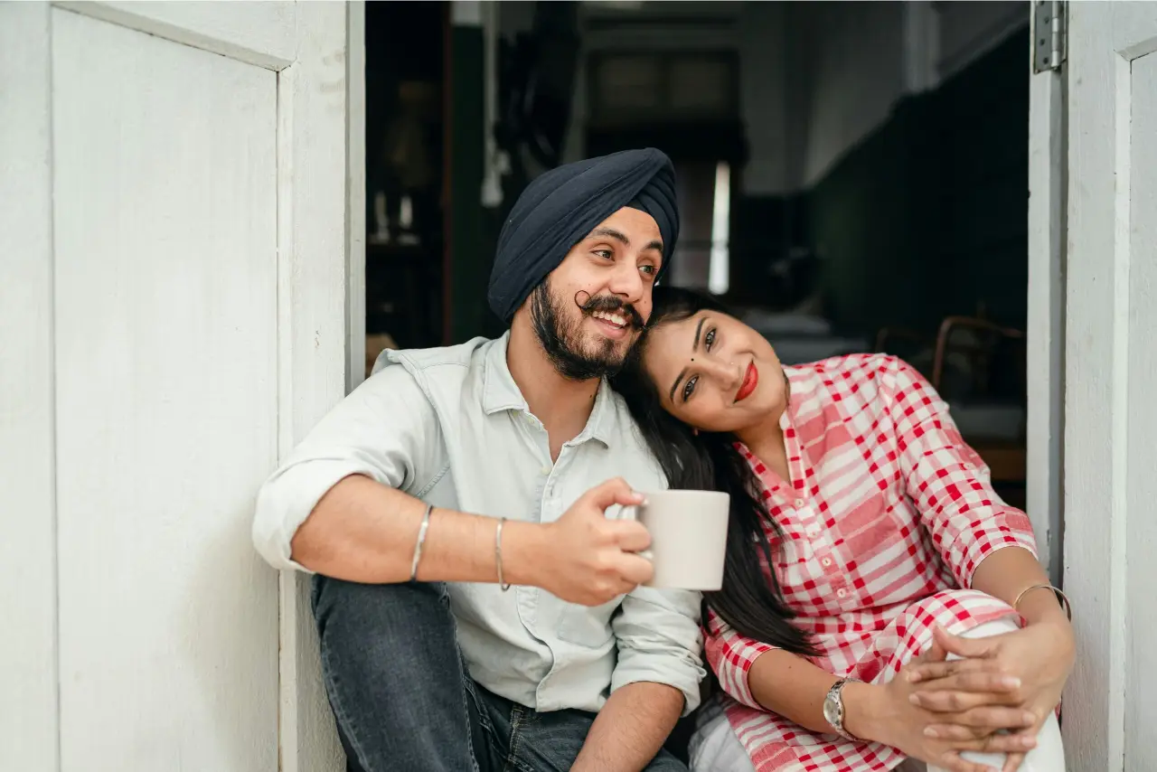 Happy Indian couple relaxing at home with coffee, embracing love and leisure. spouse visa AS consultants